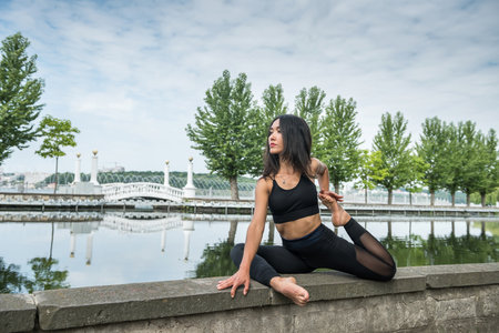 Young woman in sportwear doing fitness exercises outdoor near the lake. health lifestyle