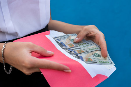 female hands in handcuffs holding an envelope with dollars. the concept of corruption and briberyの写真素材