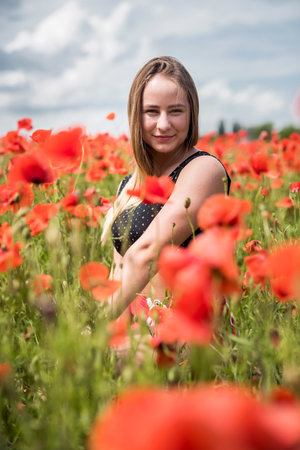 Portrait of stunning woman in sportswear posing while walking in amazing poppy field in hot summer evening, enjoy freedomの写真素材