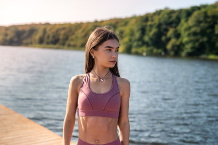 Young slim woman wearing sport clothing rest after morning exercise near lake. healthy lifestyle...