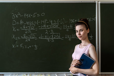 schoolgirl writing high school maths formula with chalk on blackboard, Math class algebra