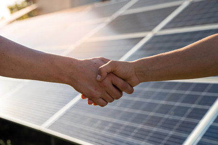Two people having a shaking hands against solar panel after the conclusion of the agreement in the renewable energyの写真素材