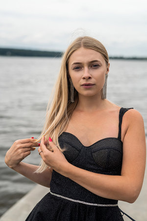 beautiful woman in black fashion dress posing near lake, summer time