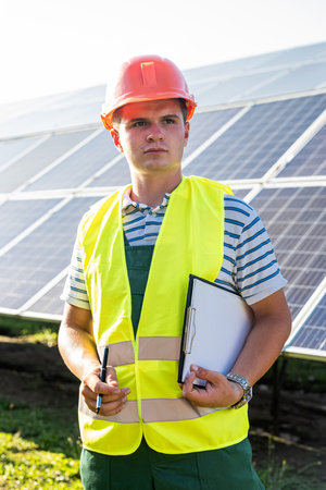 Portrait of professional electrician in helmet on solar panel stationの写真素材
