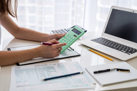 Woman filling US tax form with laptop and calculator at office. individual income tax return