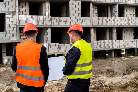 two beautiful workers in uniform on a construction site are considering a plan. construction...