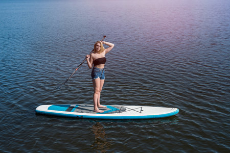 pretty girl lying on paddle board on dark blue pond water. travel or vacation concept