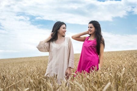 two pretty sisters enjoy freedom in wheat field, summer dayの写真素材