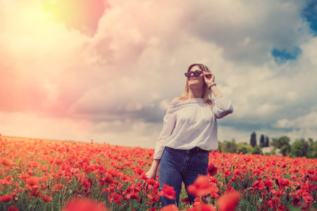 beautiful woman in a poppy field, enjoy summer time. Romantic mood nature loverの写真素材