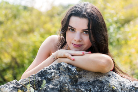 Sensual girl near a rock against the background of sand quarry or mountains. good sunny summer day tripの写真素材