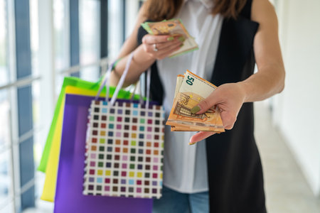 woman holding european banknotes and color shopping bags at supermarket. black friday. discount conceptの写真素材