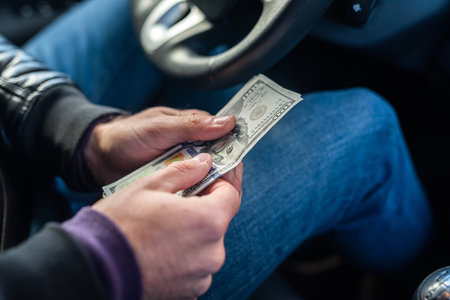 hands of a car driver holding banknotes of dollars in the middle in the car. business concept. The concept of buying a carの写真素材