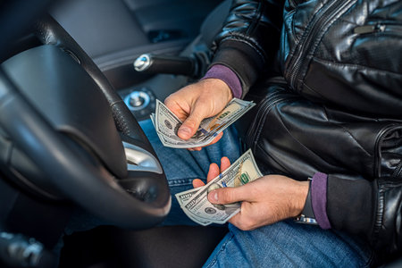 hands of a car driver holding banknotes of dollars in the middle in the car. business concept. The concept of buying a carの写真素材