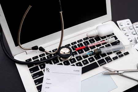 on a black background is a laptop with a stethoscope, pills, syringe, prescription. medicine concept