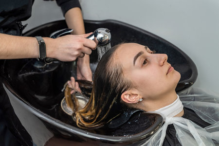 top view as a master colorist washes the hair of the head of a young girl in a beauty salon. Hair color concept. beauty salon conceptの写真素材