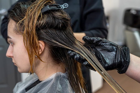 beautiful young brunette girl sitting on the procedure of hair coloring at the best master. Hair color concept.の写真素材
