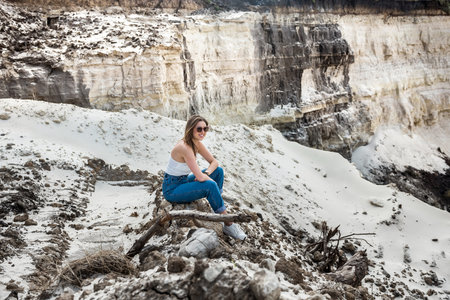Pretty woman poses against sand canyon background of rocks in hot summer sunny dayの写真素材