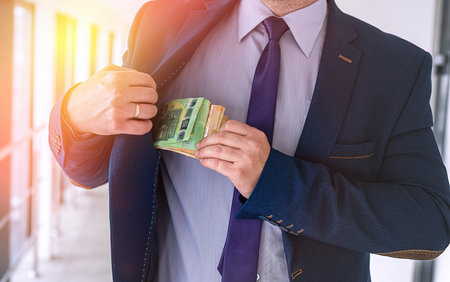 Businessman putting euro bills into pocket hit jacket. bribe corruption concept