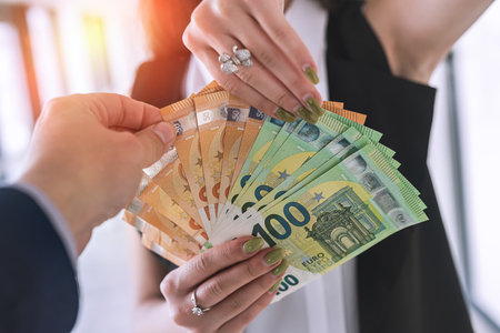 hands of a young beautiful girl hand over a large sum of new euro bills. business conceptの写真素材