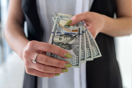 young business woman with us dollar money in hand stand at office. salary ir bribe conceptの写真素材