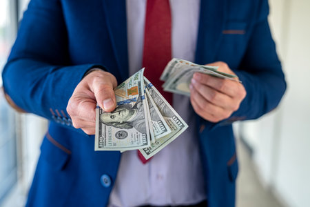 man in a suit counting of 100 dollar bills in the office. business success conceptの写真素材