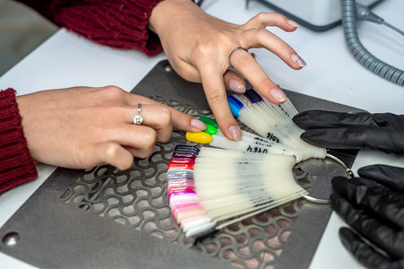 a girl who is a manicurist works on the nails of her client who went for a manicure during a...
