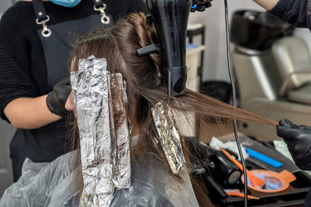 lightening dark beautiful hair with paint to further give a different color in the beauty salon. hair color conceptの写真素材