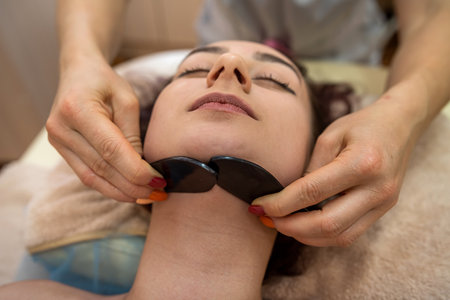 in a prestigious expensive beauty salon, clients are given a wonderful facial massage with stones to smooth out wrinkles. facial massage conceptの写真素材