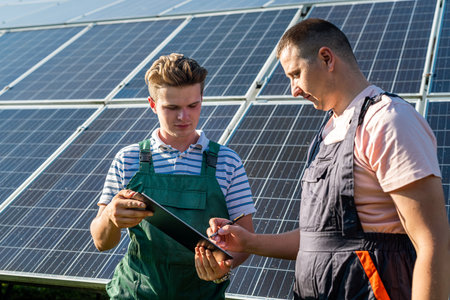 Electrical engineers examining the construction near solar energy batteries, green energyの写真素材