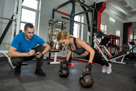 young girl is engaged in a weight training machine in the gym at the most promising coach in the city. The concept of strength training in the gymの写真素材