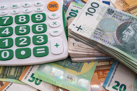 very large amounts of euro banknotes and Polish new zlotys and a calculator with a beautiful keyboard. business conceptの写真素材