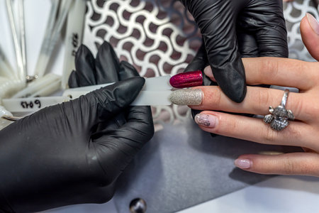 wonderful manicure master in black special gloves does a miracle with the nails of clients. manicure conceptの写真素材