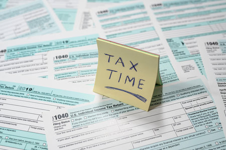 many American tax forms 1040 lie mixed with a piece of paper from a notebook on them. Document...