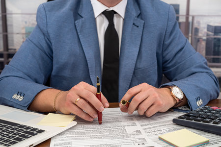 businessman man in a classic suit works with documents as tax forms of the United States 1040. The...