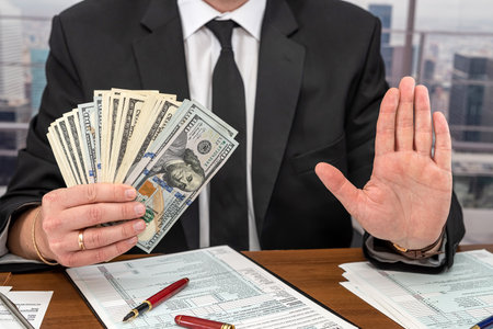 strict angry businessman in a suit from a stylist makes calculations on his own business at the table in the office. The concept of tax forms and businessの写真素材