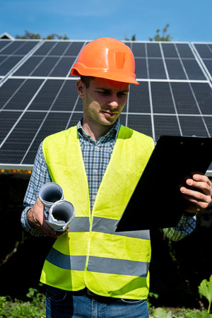 Portrait of worker in protective uniform standing before solar panels