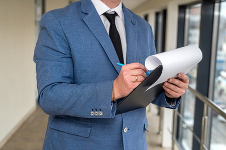young promising man in a classic suit with a tablet tie in his hands and money stands in the hallway...