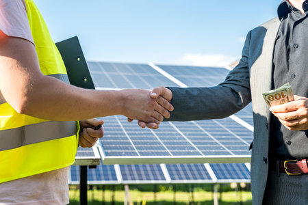 Two people having a shaking hands against solar panel after the conclusion of the agreement in the renewable energyの写真素材