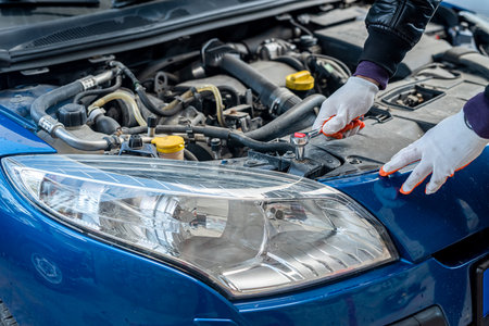 hands of a strong man in gloves inspect the car under the hood for damage. car repair concept. car inspection concept.の写真素材