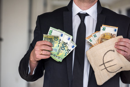 young boss businessman in expensive suit with tie holds bag with euro banknotes. Euro bag concept for manの写真素材