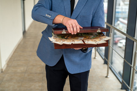 handsome young man in a classic suit with a tie holds in his hands a bag of euros. money bag concept