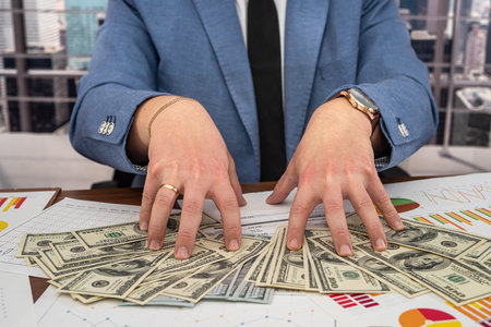 the business boss counts in his office money and graphs of profits and declines in profits. Money and graph business conceptの写真素材