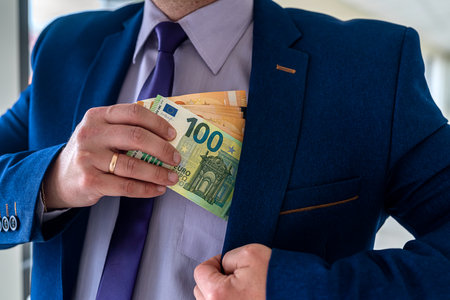 Businessman putting euro bills into pocket hit jacket. bribe corruption conceptの写真素材