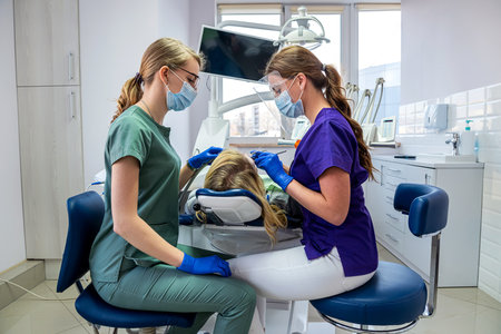 the dentist and his assistant examine the oral cavity and treat the client. treatment of teeth, care conceptの写真素材
