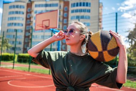 charm young woman with basketball on sports playground, summer time. sport active lifestyle. Female street ball player in action.の写真素材