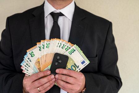 Young business man in a suit holding fan of euro banknotes. business financial transactionsの写真素材