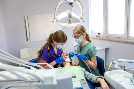 female dentist with the help of an assistant conducts a professional examination of the patient's oral cavity.の写真素材