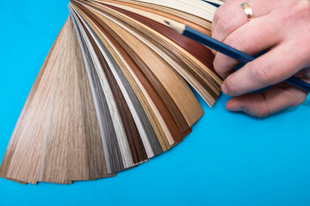 male hand choosing paint tone at color sampler isolated on blue background. different colors