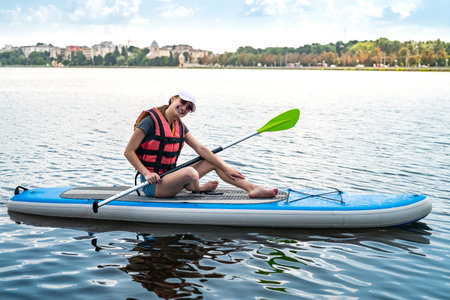 Young pretty woman in orange life vests surfs on supboard in city lake. learn and rest at nature....