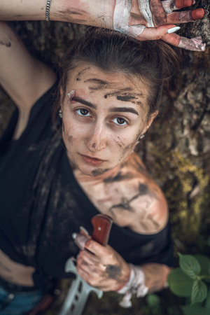 beautiful young physically healthy girl in beautiful nature with sharp knives. Concept of woman in nature with knivesの写真素材